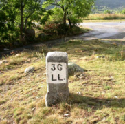 Vue d’une borne au bord d’un chemin, portant les inscriptions 3G et LL.