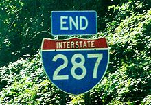 An end I-287 shield with trees in the background