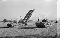 A tank with a section of bridge held out at 45 degrees in front of it, with another tank to its side