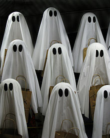 Lots of small sheets-with-eyes-style ghosts holding baskets