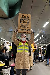 Person holds high a cardboard sign reading "food donations, follow me"