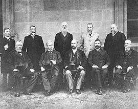 Edmund Barton is seated second from the left, surrounded by the Federal Executive Council, comprising his Cabinet ministers and the Governor-General, Lord Tennyson. Standing at the rear, left to right are James Drake, Senator Richard O'Connor, Sir Philip Fysh, Charles Kingston, and Sir John Forrest. Seated at the front, left to right are Sir William Lyne, Edmund Barton, Lord Tennyson, Alfred Deakin, and Sir George Turner. FirstMinistry.jpg