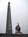 Patung pria dan wanita di depan menara.