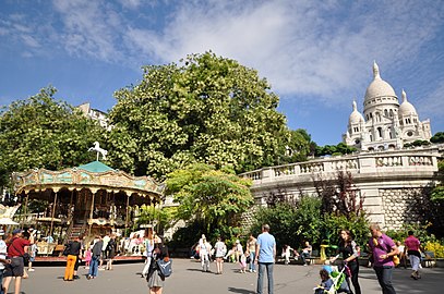 Een draaimolen op de Square Louise-Michel met op de achtergrond de Sacré-Cœur