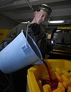 US Navy 090316-N-6597H-004 Boatswain's Mate 2nd Class George Cabeen empties used hydraulic fluid into a storage container.jpg