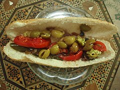 Sandwich filled with olives and sliced red tomatoes