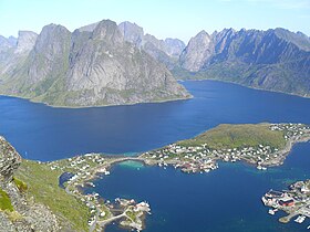 Panorama du village de Reine depuis le sommet du Reinebringen, typique des Lofoten : les reliefs escarpés tombent directement dans la mer et les routes et les habitations sont situées sur une étroite bande côtière.