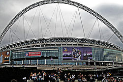 Wembley Stadium from the outside featuring a football player on a screen