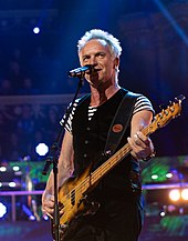 Sting cântând la chitară pe scenă.