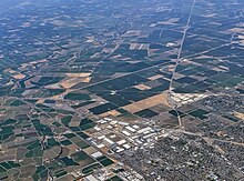 Aerial view of the northeastern part of Tracy (lower right) and land to the south and east, in 2021. The warehouse distribution and fulfillment centers in the northeast corner of the city are at lower center. Behind and to the right is the Defense Logistic Agency's Tracy Defense Distribution Depot (which is just outside Tracy to the east). Tracy aerial.jpg