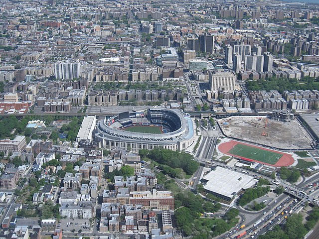 Yankee Stadium (centro), Tribunal do Condado do Bronx e o Grand Concourse em direção ao topo. À direita do atual estádio está o local de seu antecessor