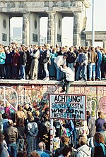 People atop the Berlin Wall near the Brandenburg Gate on 9 November 1989