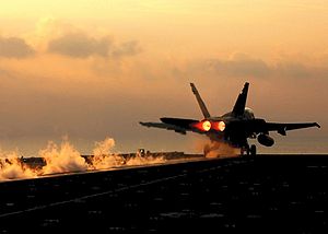 מטוס מדגם F-18 ממריא מנושאת מטוסים בעזרת מעוט השיגור ומפעיל מבער אחורי.