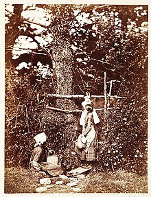 Three girls in 19th-century clothing, seated and stood outside.