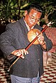 Cambodia, 21st century. Yoeun Mek plays a Kse diev heterochord stick zither, which uses a gourd for a resonator.