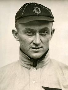 Portrait of a man wearing a high collar, held closed with a safety pin.