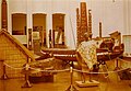 Māori man holding a bird-spear. War canoe in background (photo taken at Dominion Museum in Wellington, New Zealand, during July, 1980)