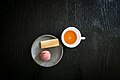 A cup of guava punch with a piece of sugar cane and cinnamon bread.