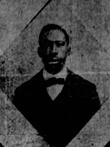 A black and white photograph of a black man in a suit and bow tie.