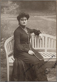 The photograph of a woman wearing pince-nez glasses seated on an outdoor bench holding a lorgnette