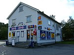 «Kiosk» kan også brukes om butikker som selger kioskvarer selv om bygningene er større enn små buer. Arhaug kiosk på Gruben i Mo i Rana ble drevet 1971–2009. Foto: 2007