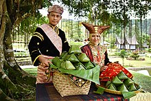 Minangkabau people wearing traditional dress and serving Kabaka rice with Rumah adat background Nasi kabaka Minangkabau.jpg