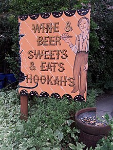 Photograph of an orange sign showing a man holding a plate with food, along with the text "Wine & Beer", "Sweets & Eats", and "Hookahs"