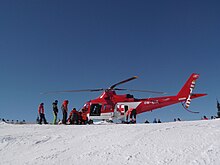 A mountain rescue helicopter on a snowy hill