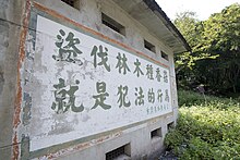 An forested old house, with a slogan attacked to the back