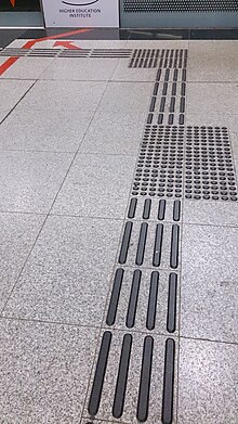 Photo of tiles with tactile rubber lines or grids of dots forming a path