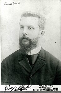 Portrait en noir et blanc d'un homme barbu portant un costume et une cravate.