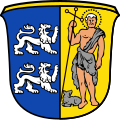 Gemeinde Frensdorf Gespalten von Blau und Gold; vorne übereinander zwei linksgewendete, schreitende silberne Löwen, hinten der heilige Johannes der Täufer in schwarzem Fellgewand, in der Rechten einen schwarzen Kreuzstab haltend, zu seinen Füßen ein schwarzes Lamm.[9]