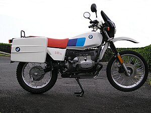 Black BMW R 80 G/S pictured on gravel at the edge of a lake