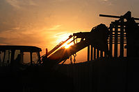 A U.S. Marine with Operations Platoon, Engineer Company, Combat Logistics Battalion 5, 1st Marine Logistics Group (Forward) directs a backhoe - building barriers to guard a checkpoint near Fallujah, Iraq. (December 2006, USMC photo) 1stMEU Backhoe 061221-M-4937G-059.JPEG