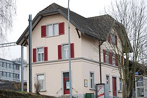 Three-story building with beige walls and red shutters