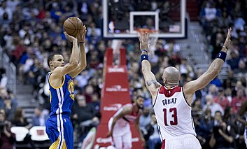 Stephen Curry attempting a jump shot over Marcin Gortat Stephen Curry (33140701266).jpg