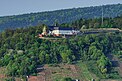 Blick auf das in der Ferne liegende Kloster auf dem Berg, am Hang Bäume und weiter unten bewirtschaftete Flächen