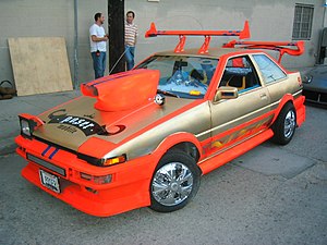 T-Mobile's 1985 Toyota Corolla Sport GT-S coupe "Poser Mobile" advertisements created a stereotypical caricature "rice burner" or "boy racer" car typical of the import scene, whose appearance and behavior is comically aspirational and "phony". Poser.JPG