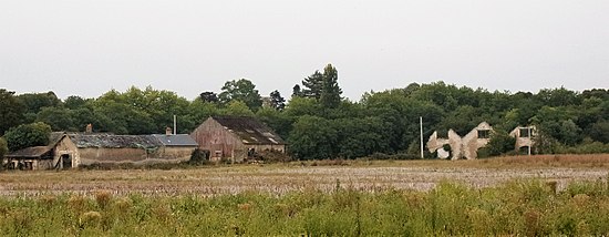 Photographie en couleurs de bâtiments en ruine et envahis par la végétation