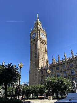 Sand-coloured building of Gothic design with large clock-tower.