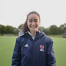 A woman in an Adidas shellsuit top marked "Great Britain" standing in a playing field