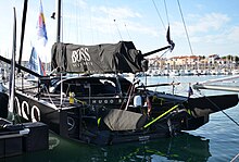 Vue trois quarts arrière d'un voilier noir, amarré dans le port.