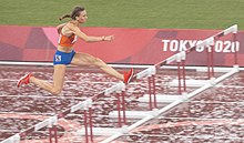 Photo of Femke Bol in the air while passing a hurdle seen on her right side