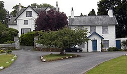 two white houses with gables on a narrow road with trees