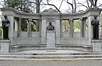 Three bronze statues on the left, center, and right of a larger curved stone structure