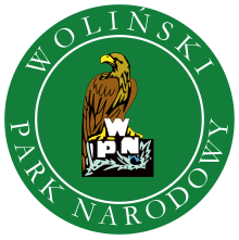 W centralnej części zielonego koła schematycznie przedstawiony bielik, siedzący na wpisanych w roślinność literach „WPN”, ustawionych w piramidę z „W” na górze. Wzdłuż obwodu koła napisy: na górze „Woliński”, na dole „Park Narodowy”.