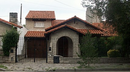 Typical vault-shaped porch on front, false front gable, attached garage with dormer on top and chimney