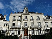 La maison en totalité, blanche avec deux étages et cinq fenêtres de large, avec sa grille de clôture.