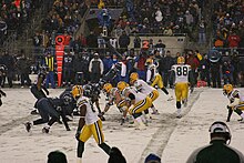 Packers and Seahawks players lining up before the snap on a snowy football field