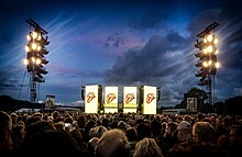 The Rolling Stones Stage at Hamburg Stadtpark. It shows the crowd in the foreground and the huge yellow illuminated screens of the stage in the background.